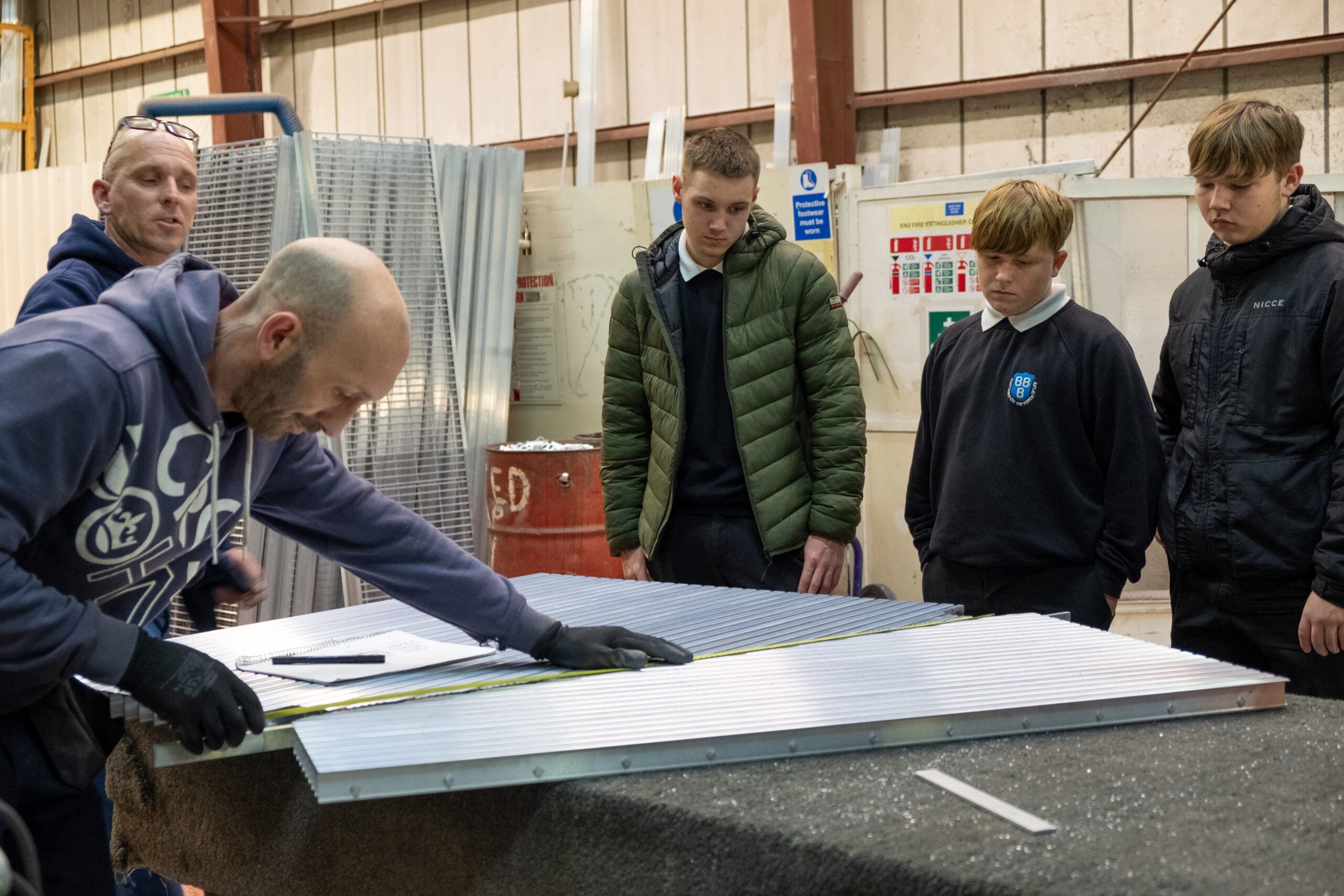 Students and engineers reviewing technical measurements for aluminium flooring production during a factory tour at Neaco.